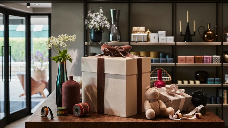Illustration eines warm beleuchteten Geschenkladens mit Regalen, Bändern und kleinen Souvenirs